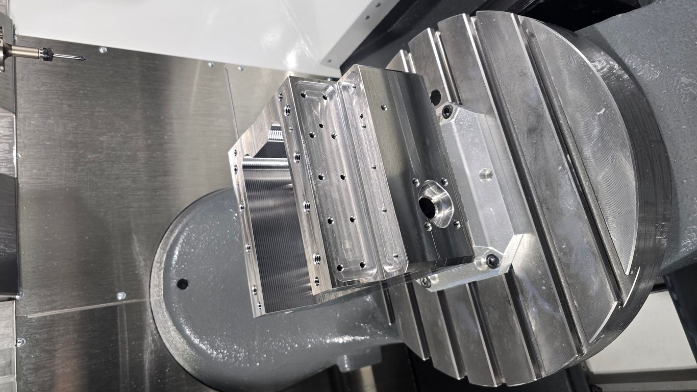 Close-up of a CNC machine with a metal workpiece on a rotary table.