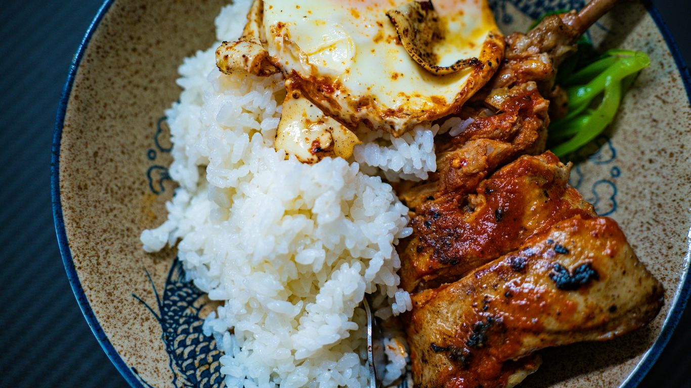 a plate with rice, meat and a fried egg