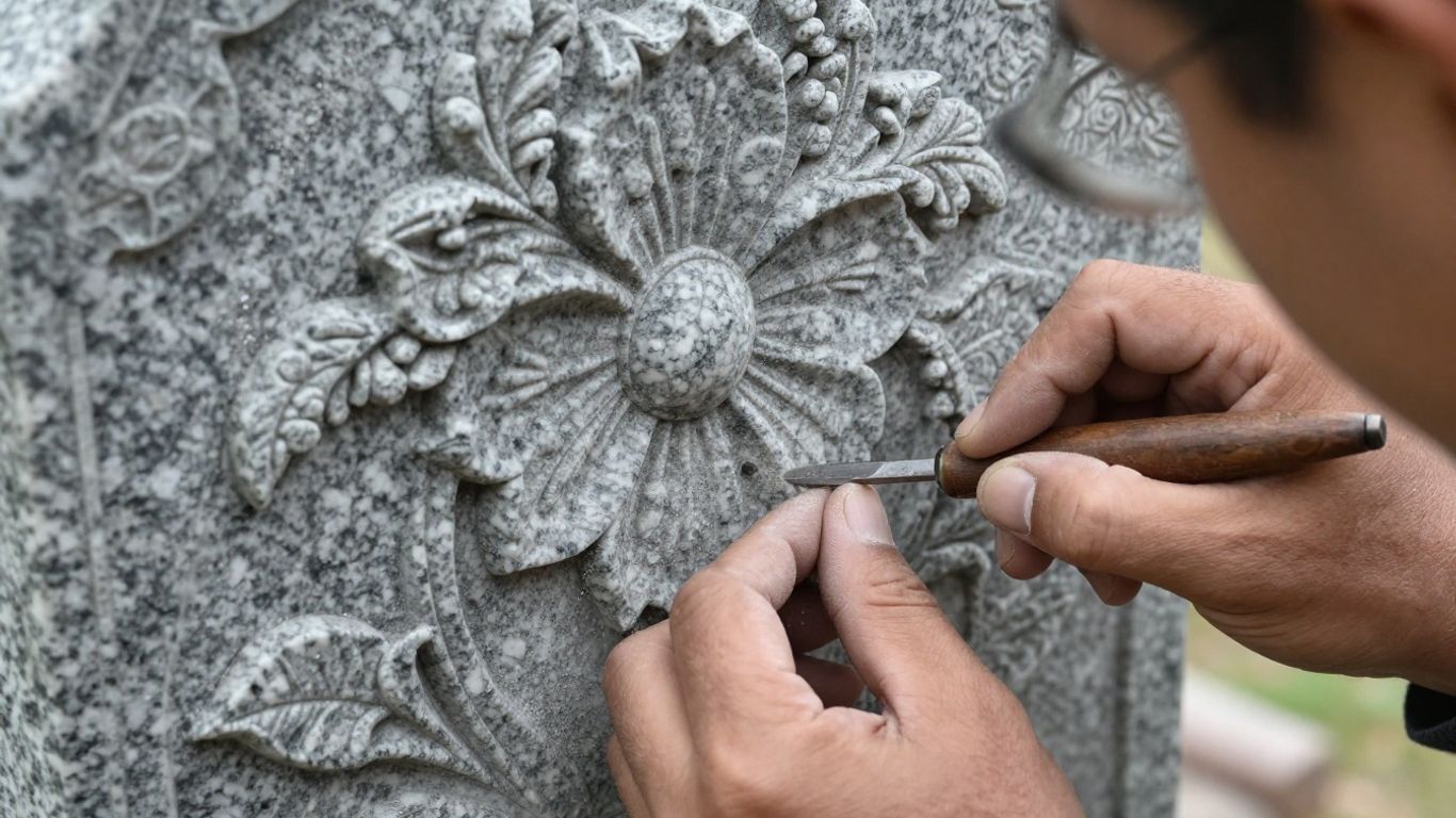 Hands carving a custom headstone with floral design.