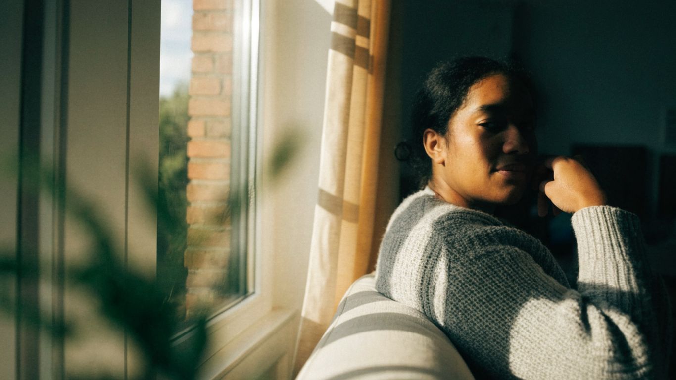 A person sitting near a sunny window indoors