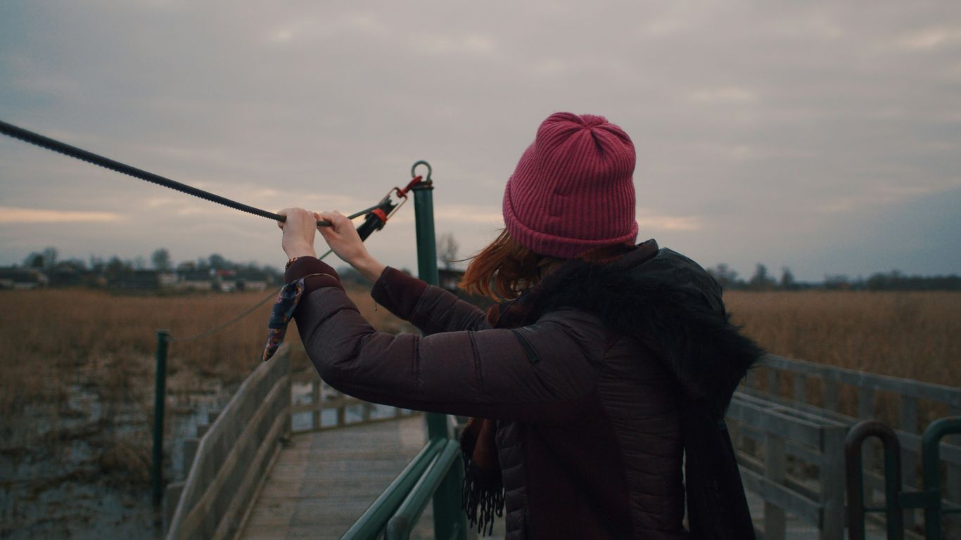 woman in black jacket and red knit cap holding on railings