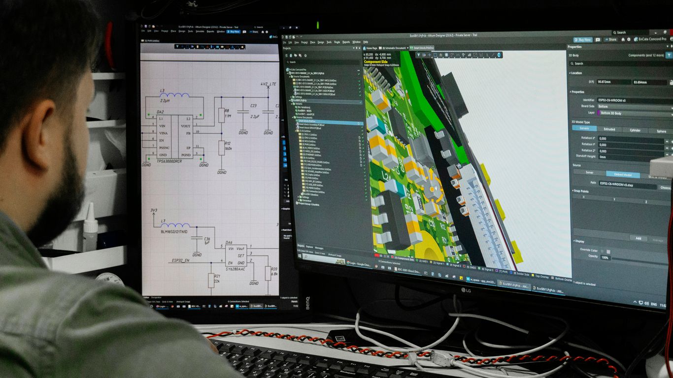 Man looking at circuit board design on computer screen.