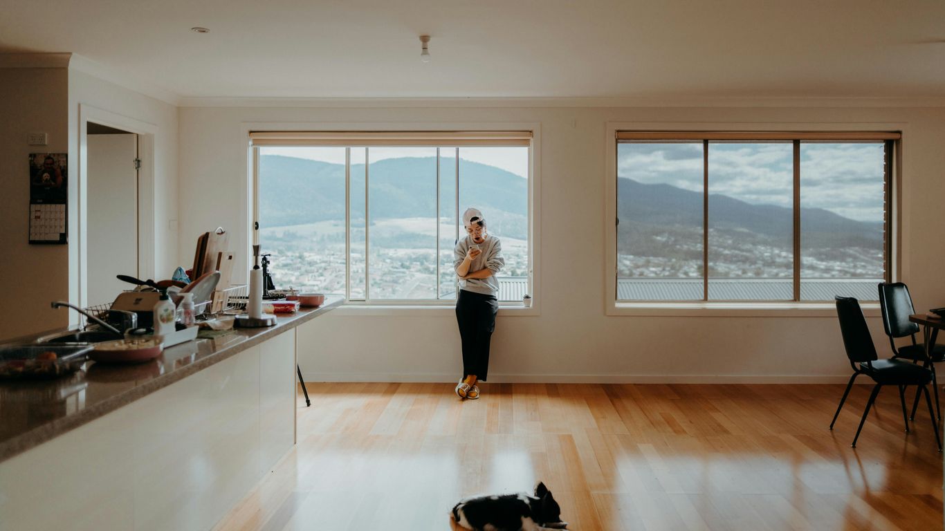 woman in white t-shirt and black pants standing near window
