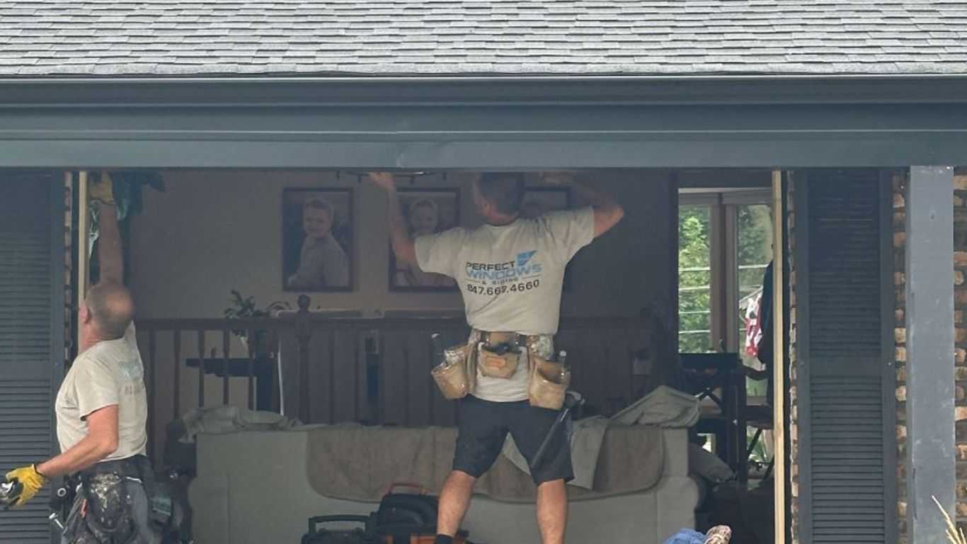 Workers installing a large window into a house.