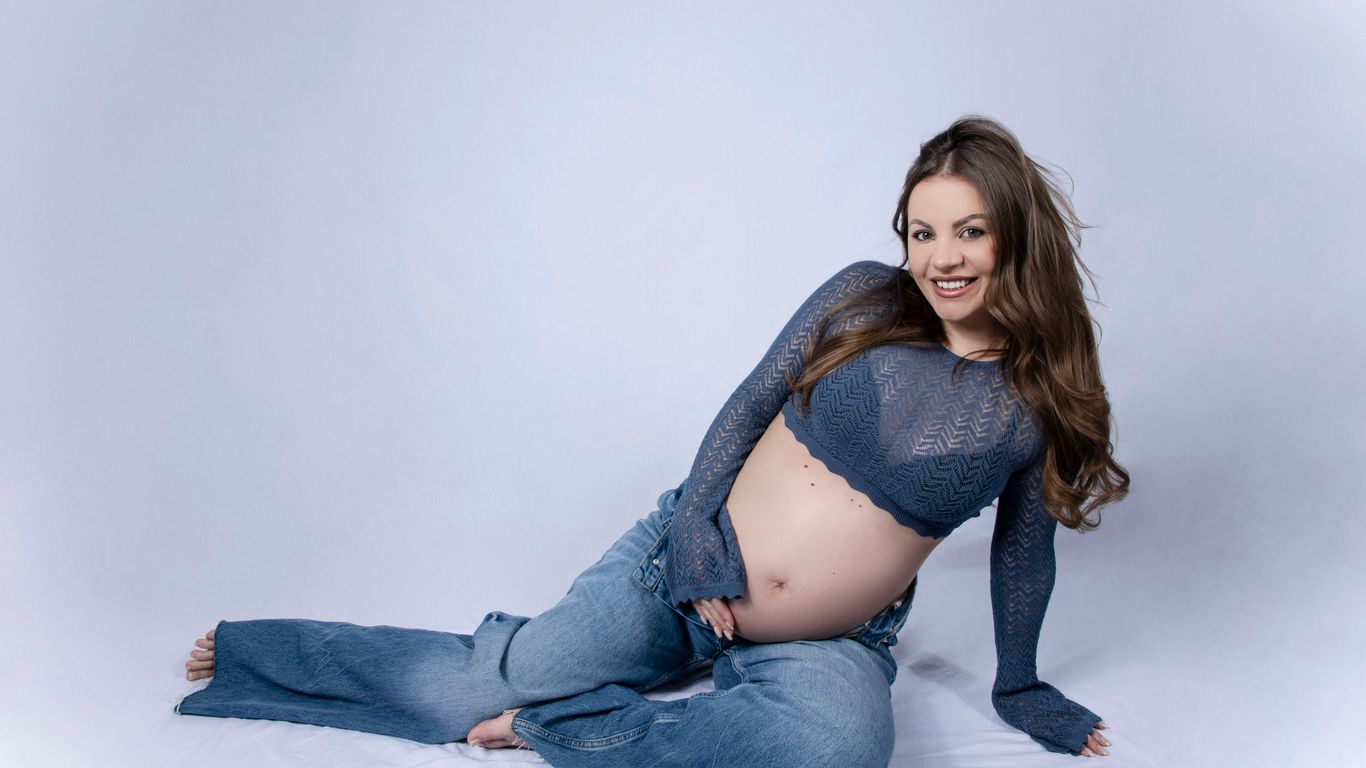 Pregnant woman in jeans and blue top smiling