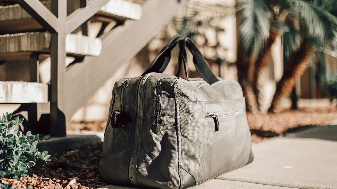 A rolled yoga mat beside a travel bag