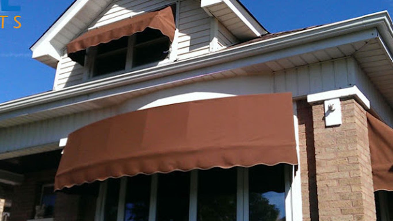Brown awnings cover the windows of a brick and siding house.