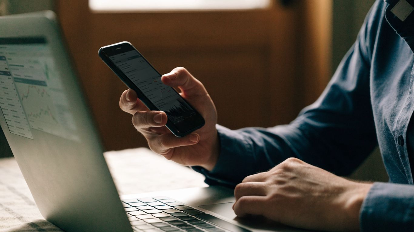 Trader reviewing account information and charts on a smartphone