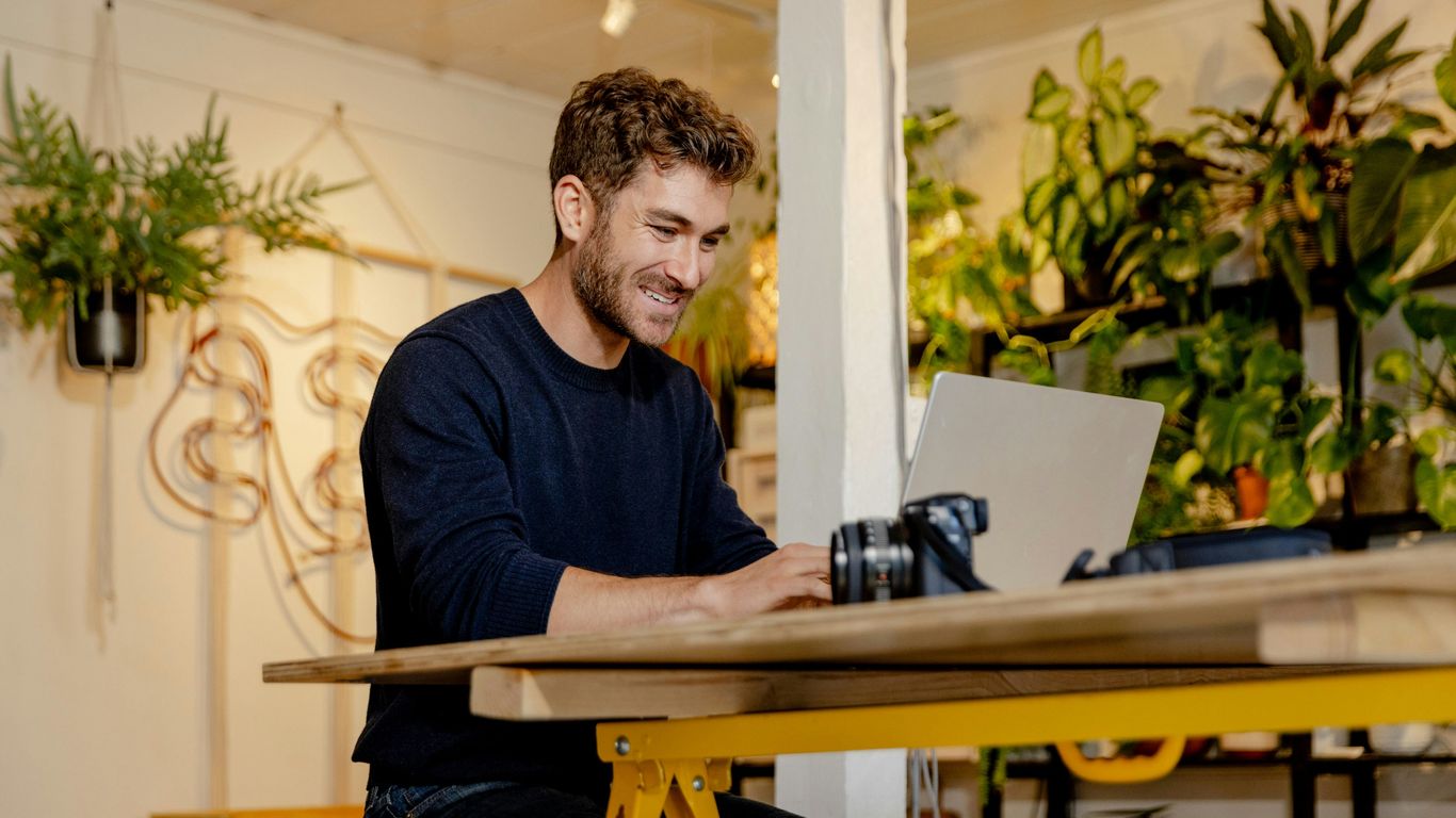 A man sitting at a table using a laptop computer