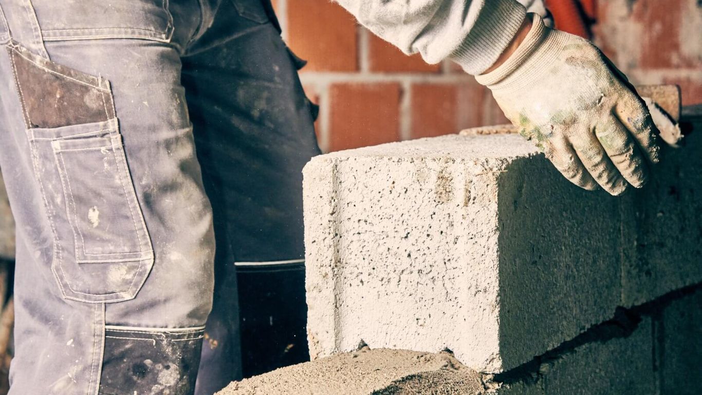 A person is laying a concrete block on a wall.
