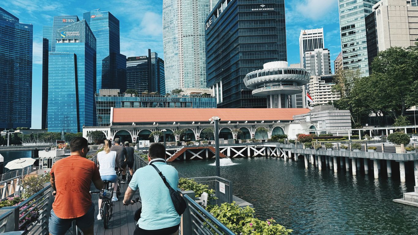 People cycling along a waterfront with city buildings