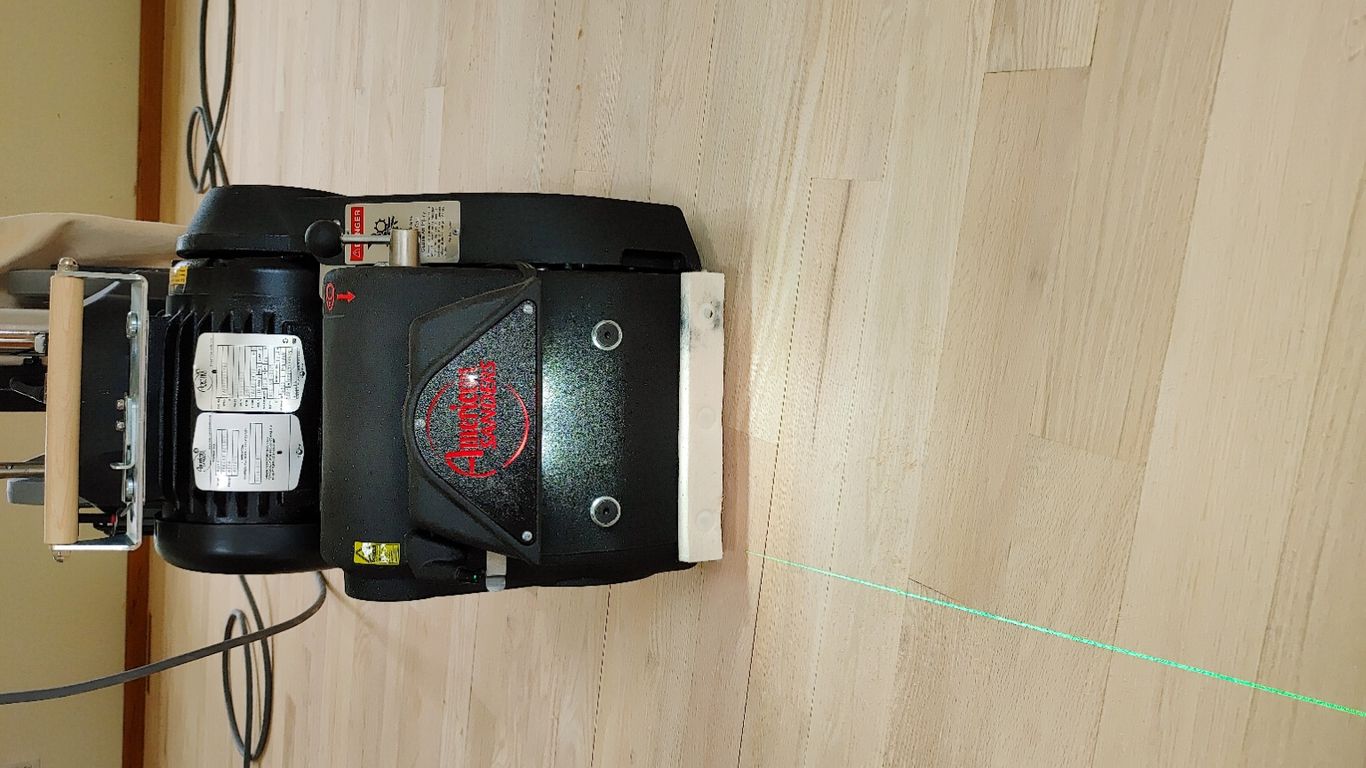 Image of a floor sander with a laser line on wood.