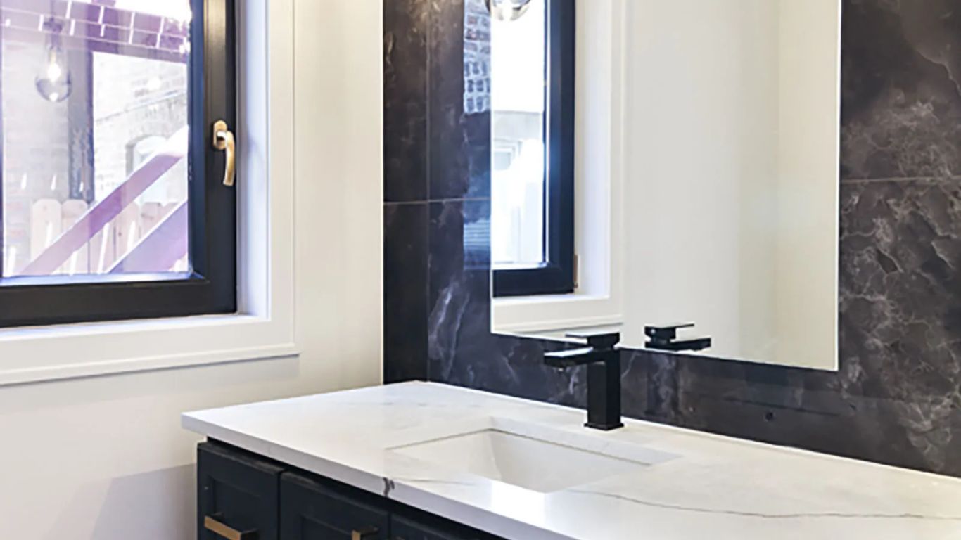 Modern bathroom vanity with dark blue cabinets and gold hardware.