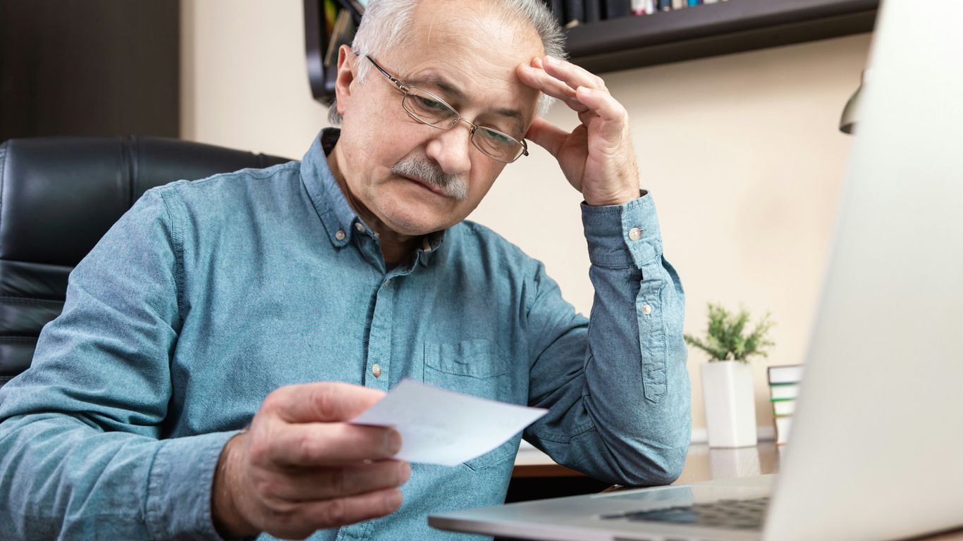 a man holding a pen and looking at a laptop