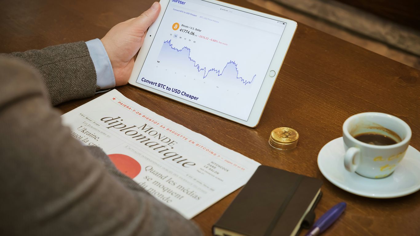 a person sitting at a table with a tablet and a cup of coffee
