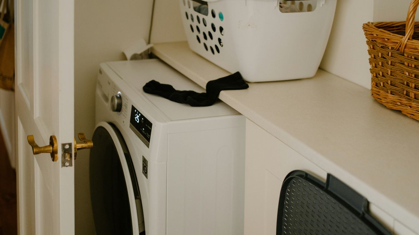 White washing machine with laundry basket and sock.