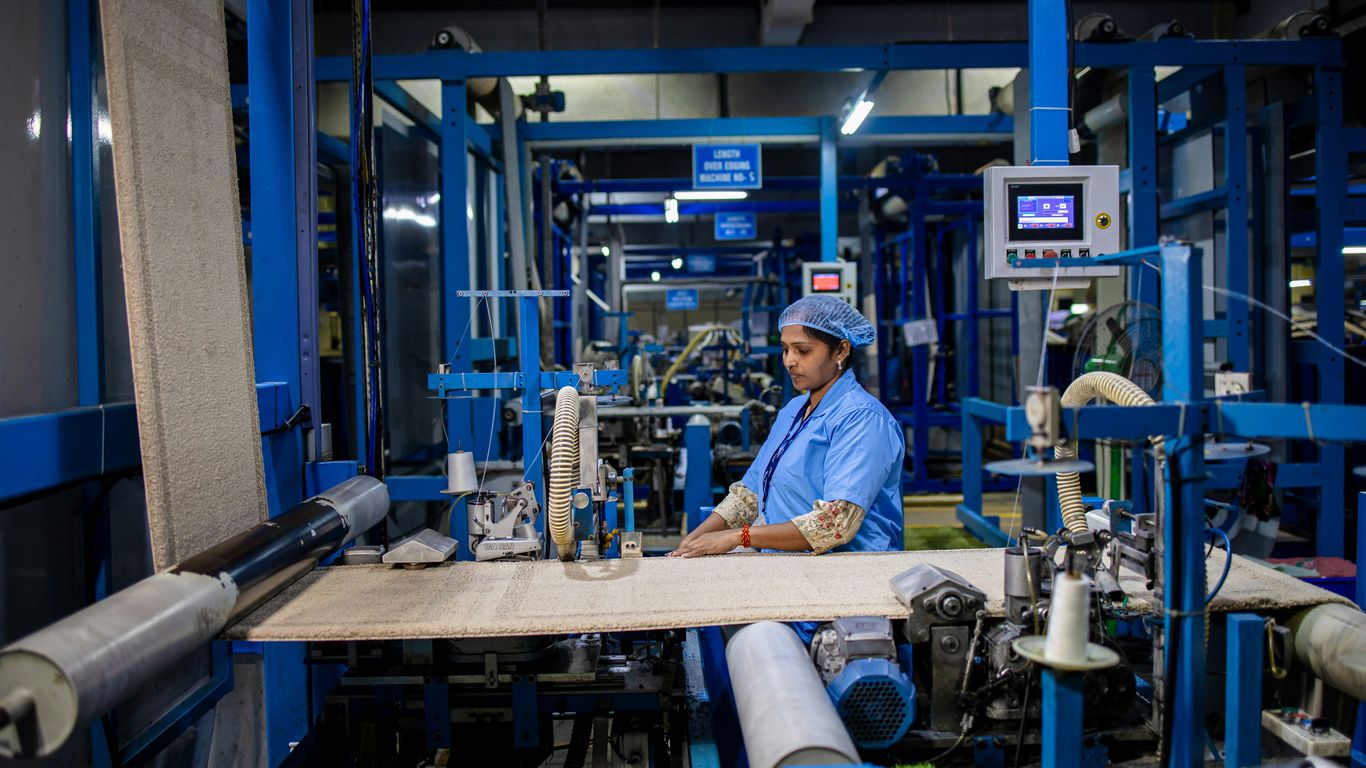 A factory worker operates textile machinery.