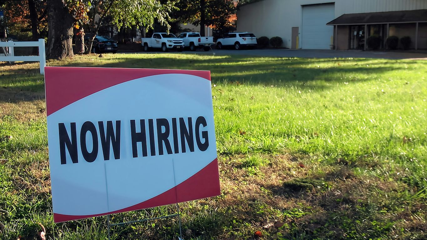 a now hiring sign in front of a building