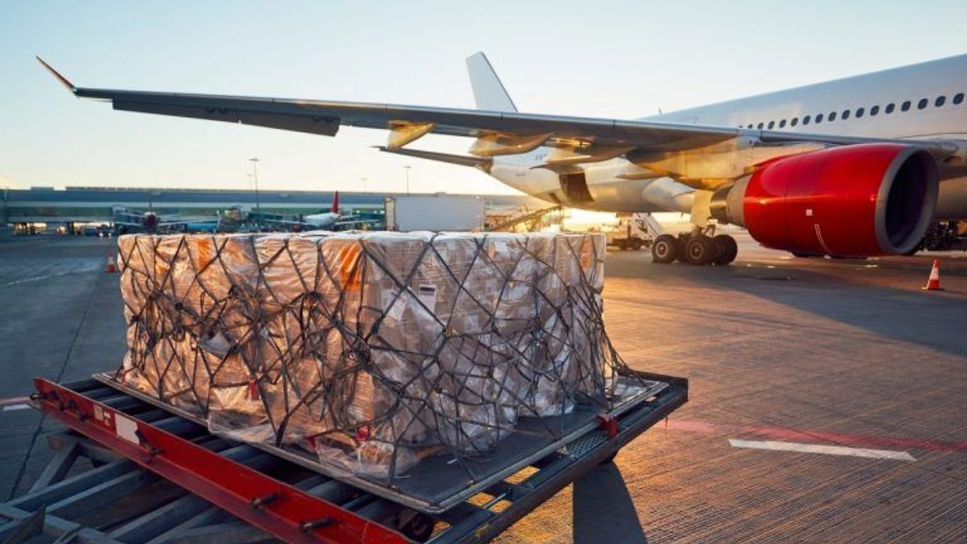 Cargo being loaded onto an airplane at an airport tarmac.