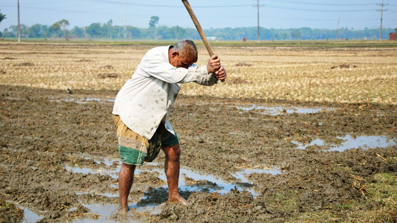 man in white shirt and green shorts holding brown wooden stick during daytime