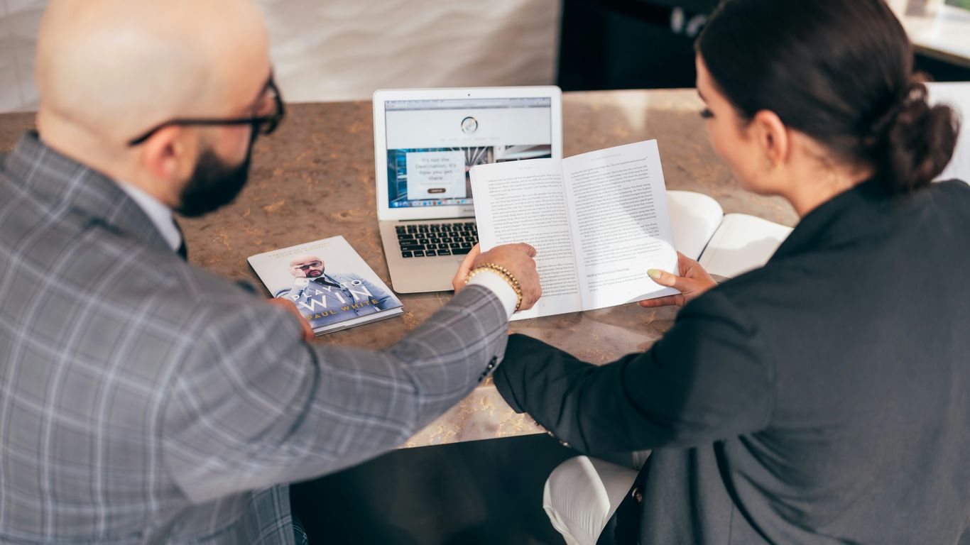 man in black suit jacket holding white printer paper