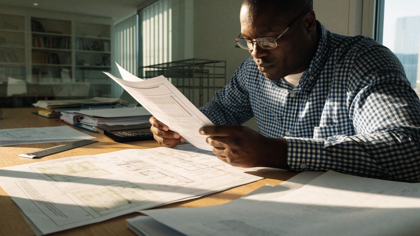 Engineer reviewing structural standards beside drawings