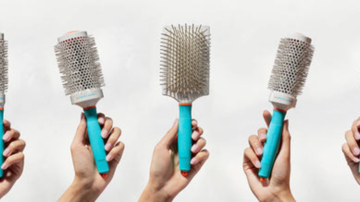 Five different hairbrushes held against a white background.