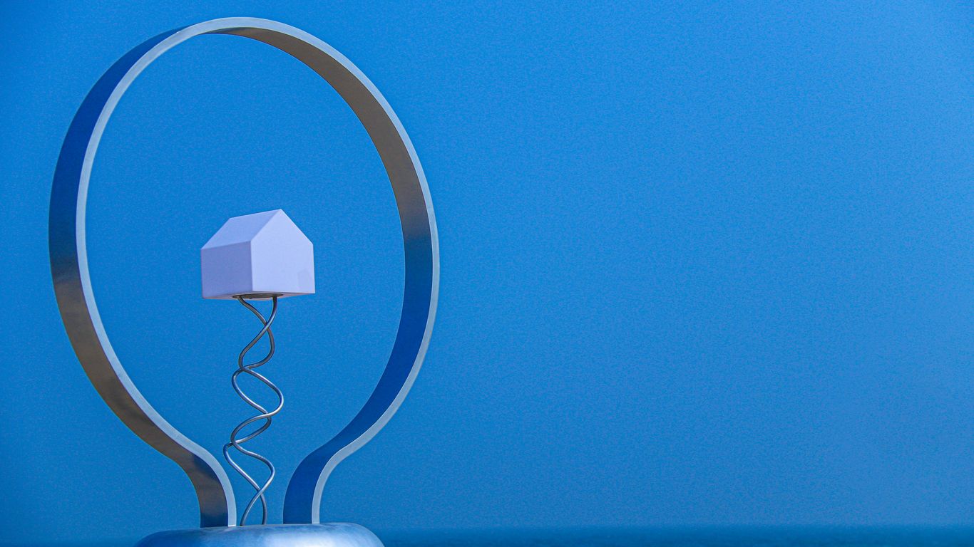 A miniature house inside a lightbulb on blue background