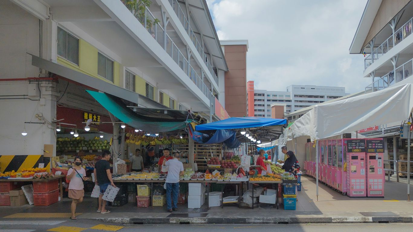 a group of people standing around a fruit stand