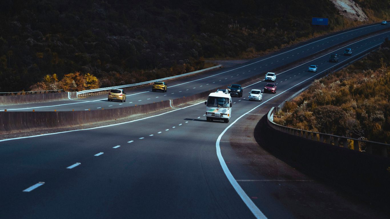 a highway filled with lots of traffic next to a hillside
