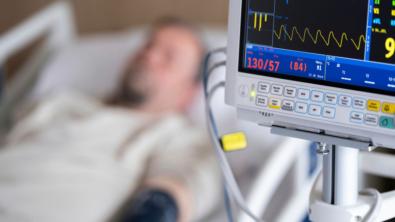 a man laying in a hospital bed next to a monitor