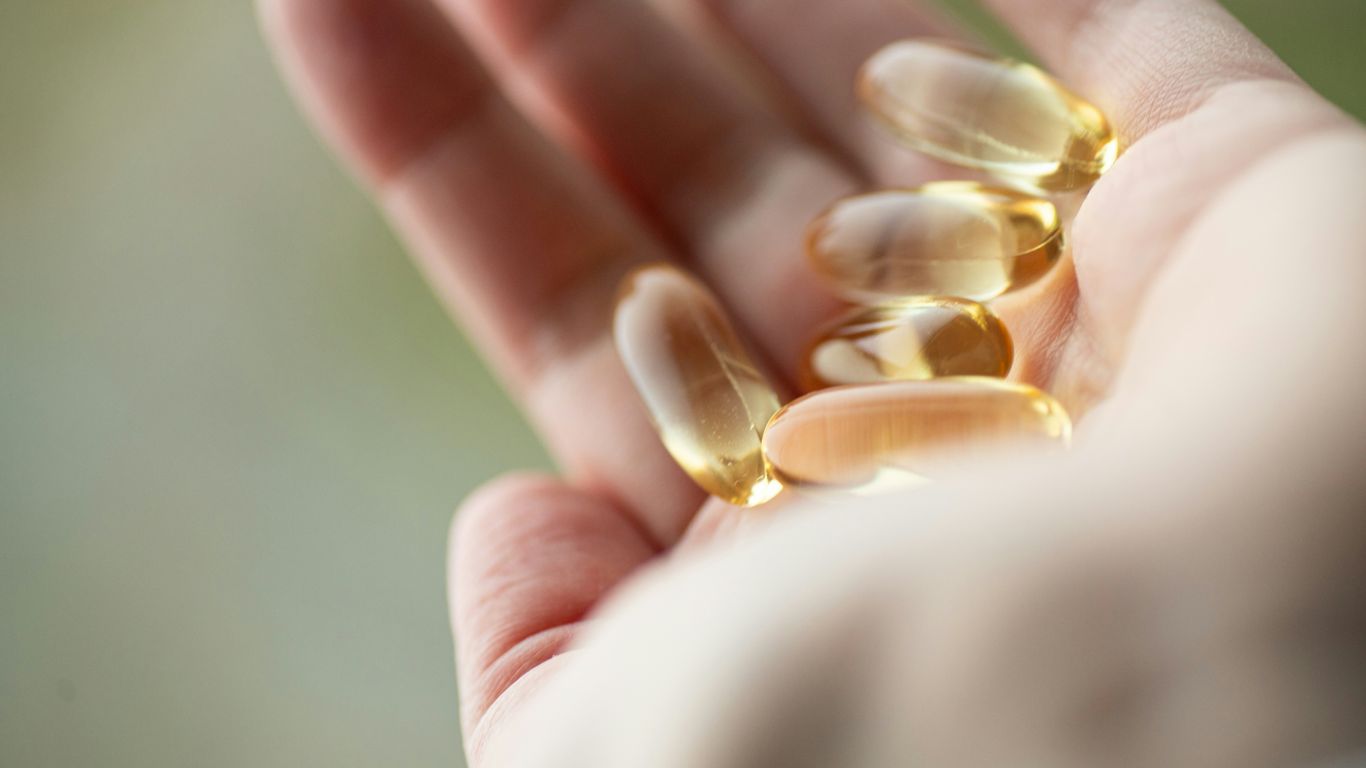 A person holding a handful of pills in their hand