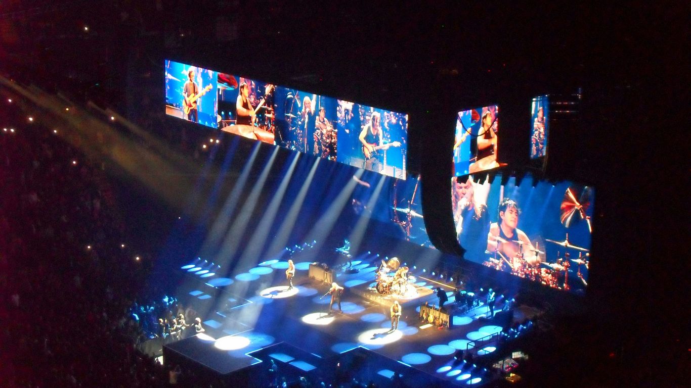 Live band performing on a brightly lit concert stage.