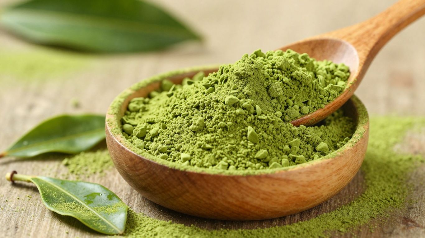 Scoop of vibrant green matcha powder with tea leaves.