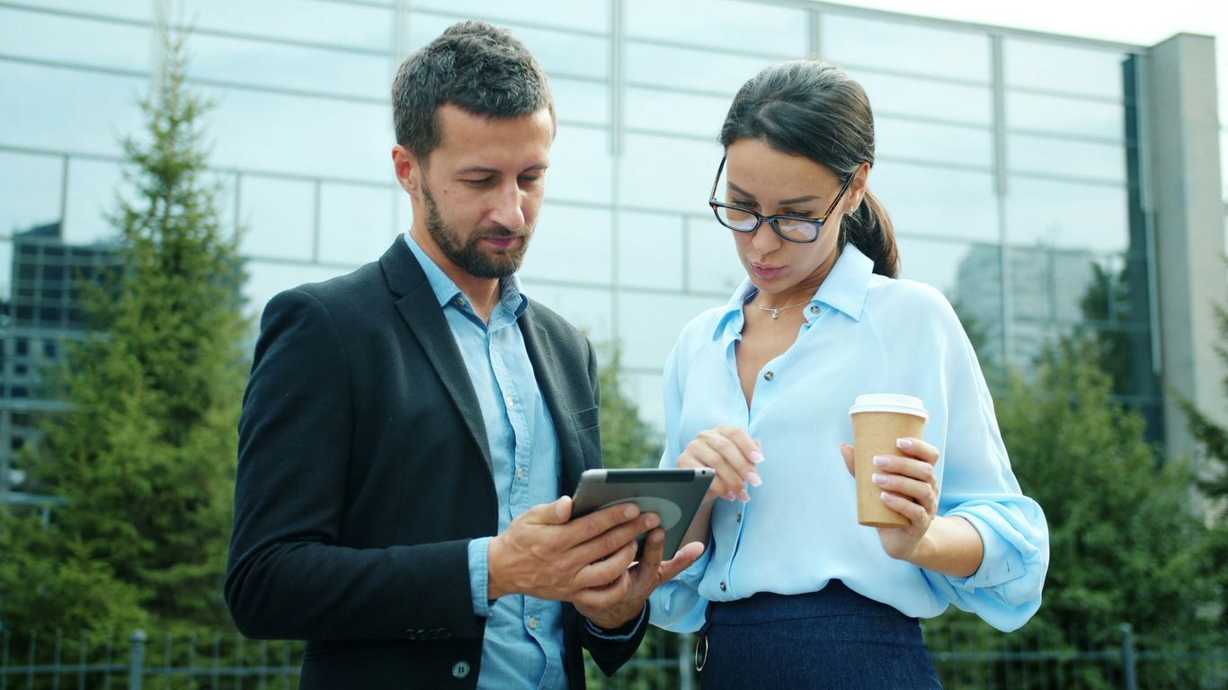Two business people looking at a tablet outside.