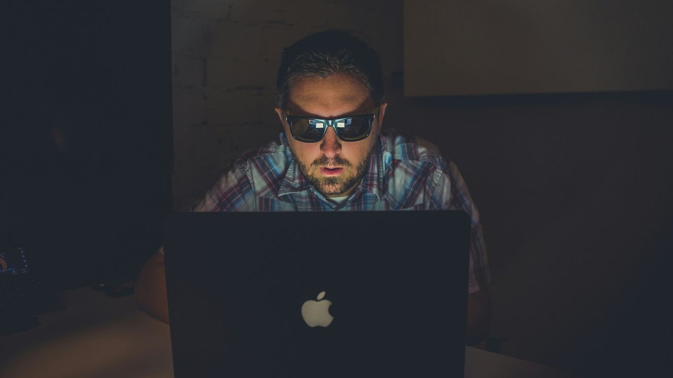 man wearing sunglasses using MacBook