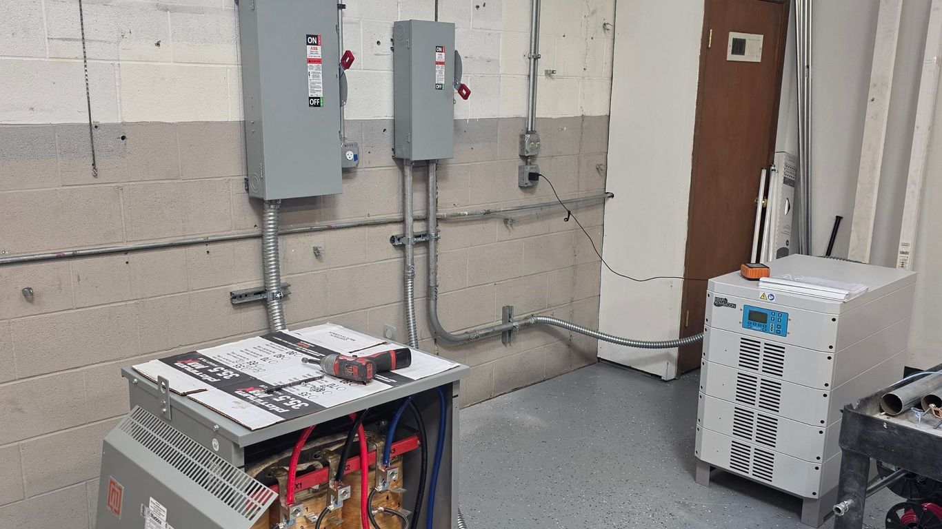 Electrical equipment, including transformers and control panels, in a room.