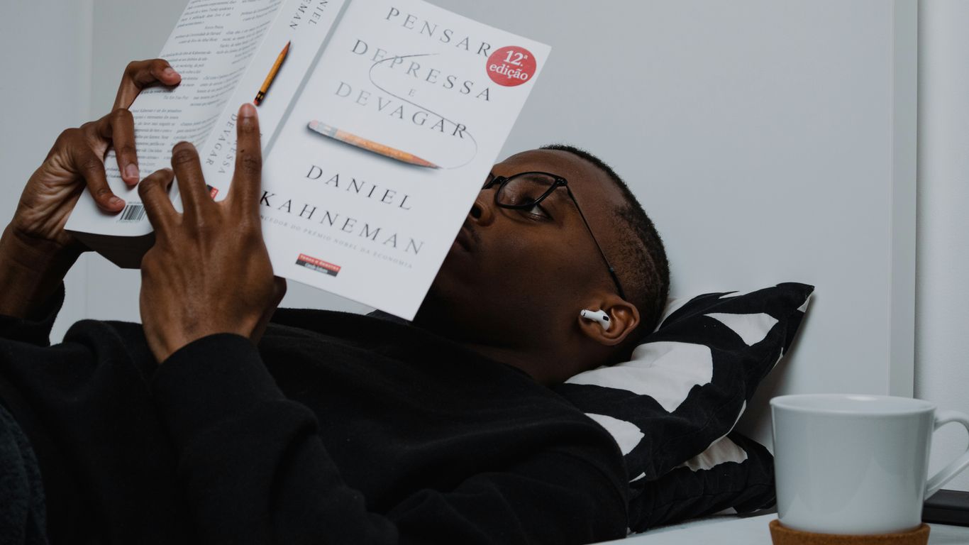 a man reading a book while holding a cup of coffee