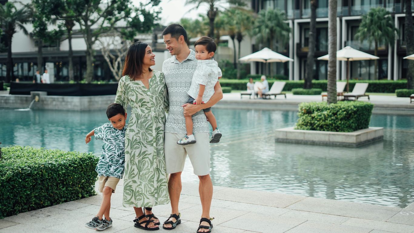 Family posing by the resort pool on a sunny day