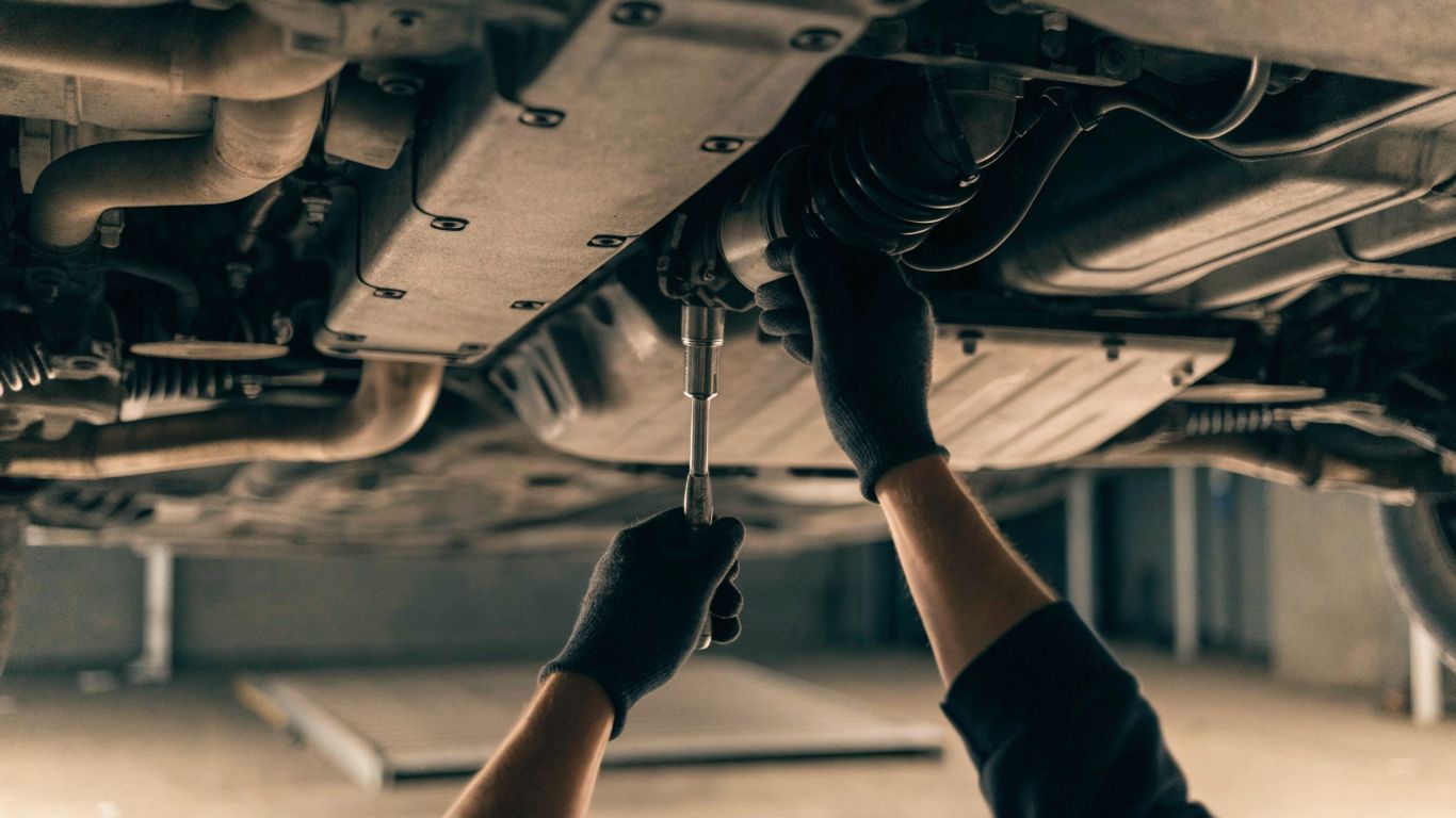 Mechanic accessing a starter beneath an SUV