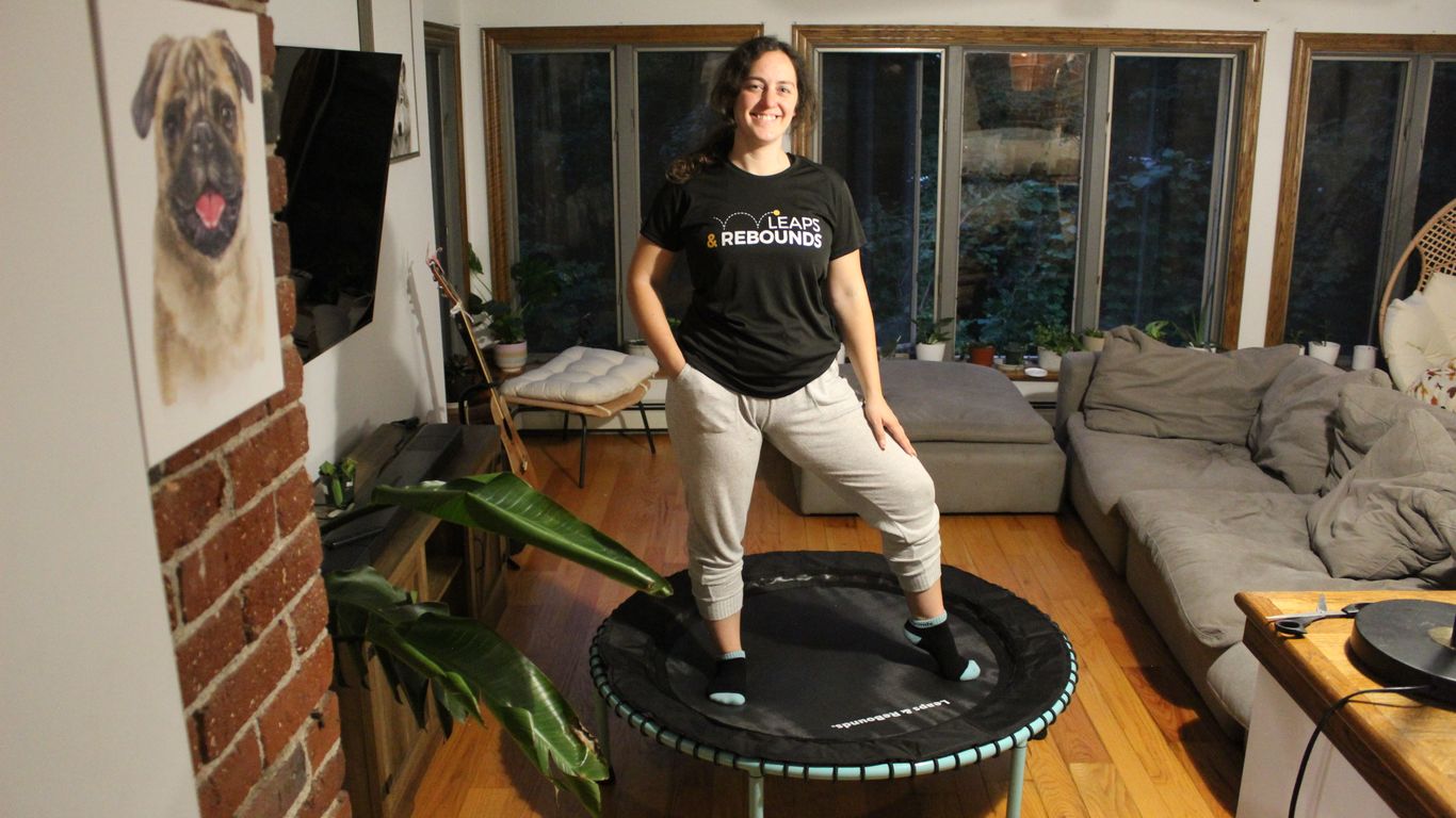 Person standing on mini trampoline in cozy living room setting.