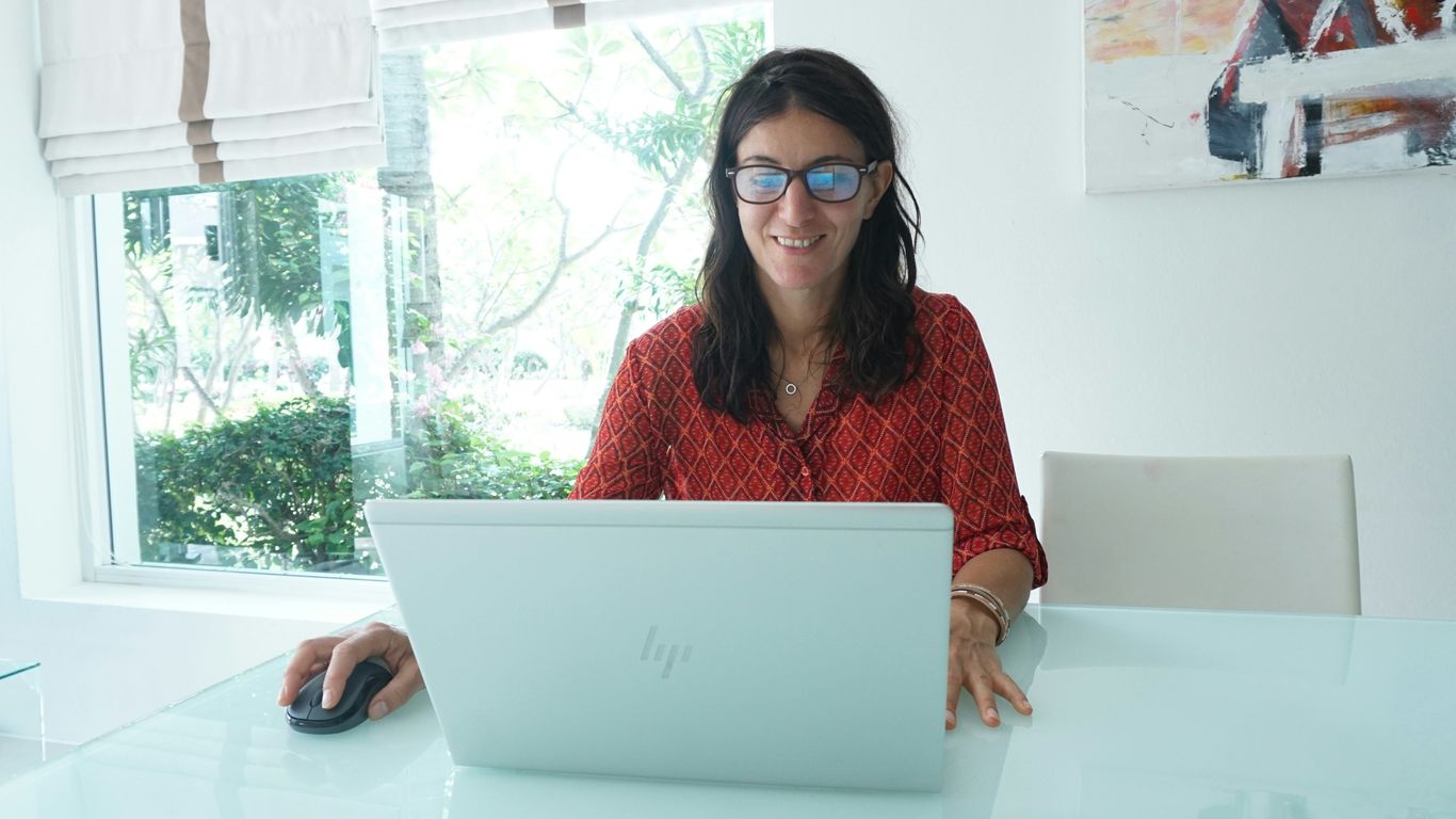 Woman smiles while working on a laptop.