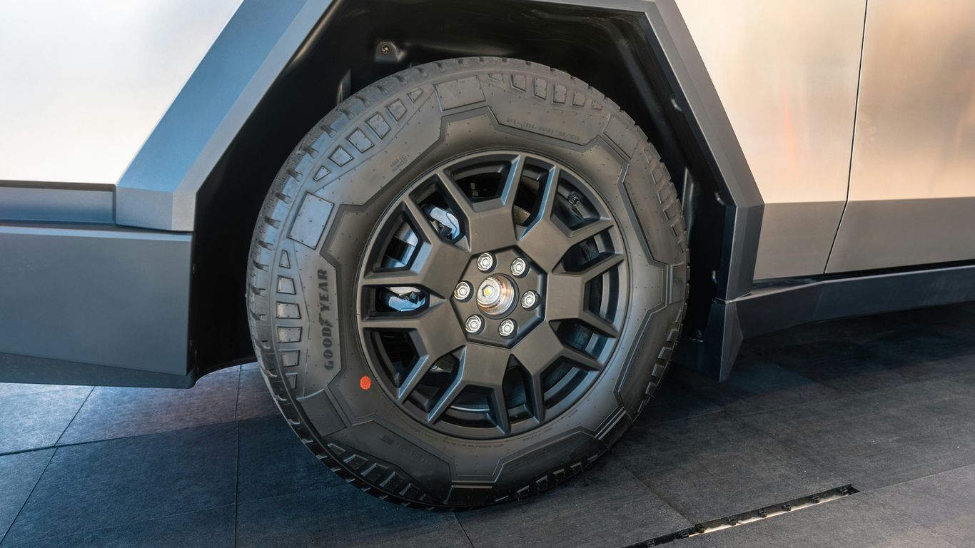 A silver vehicle with a large tire on the side of it
