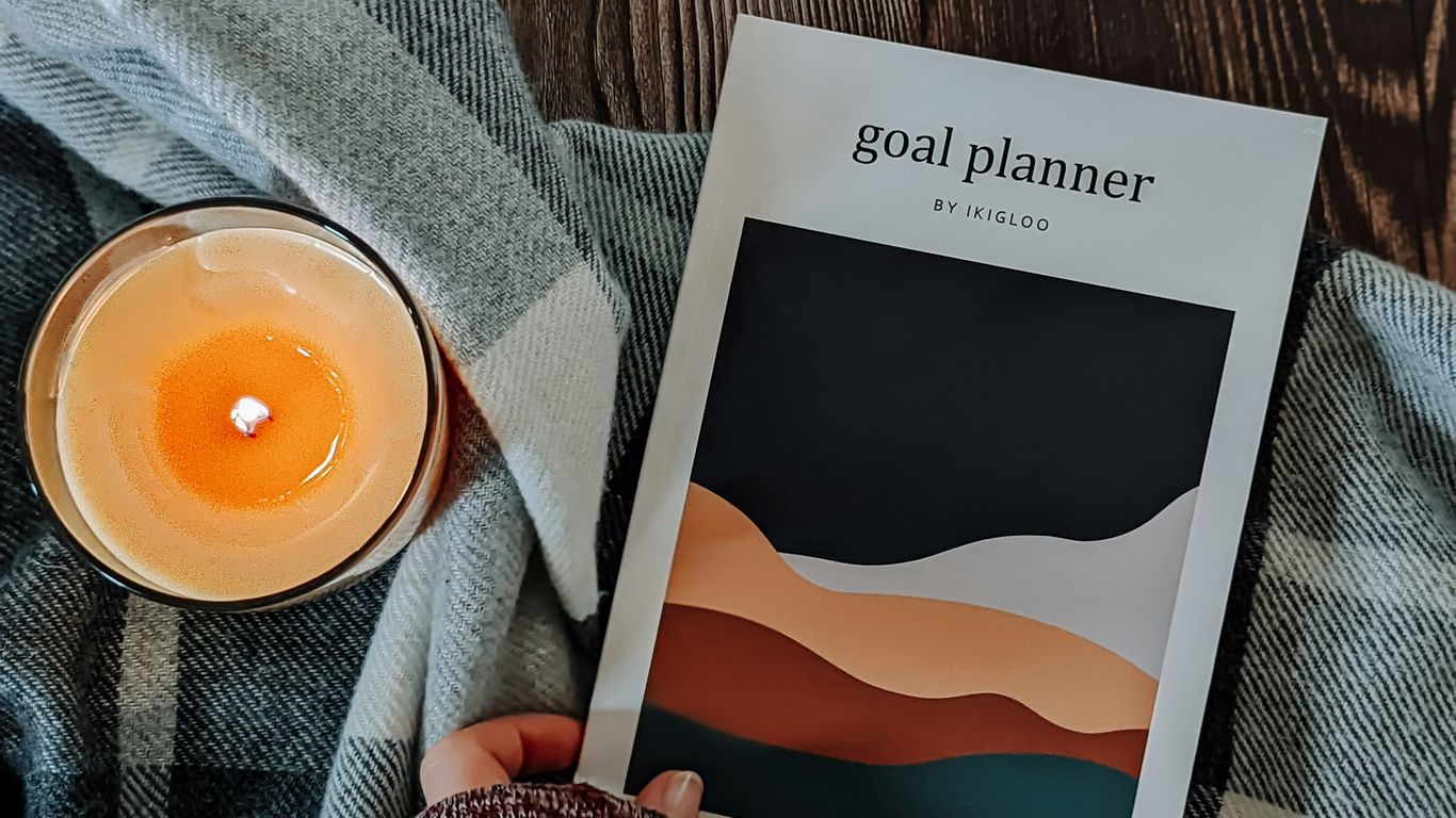 a person holding a book next to a candle