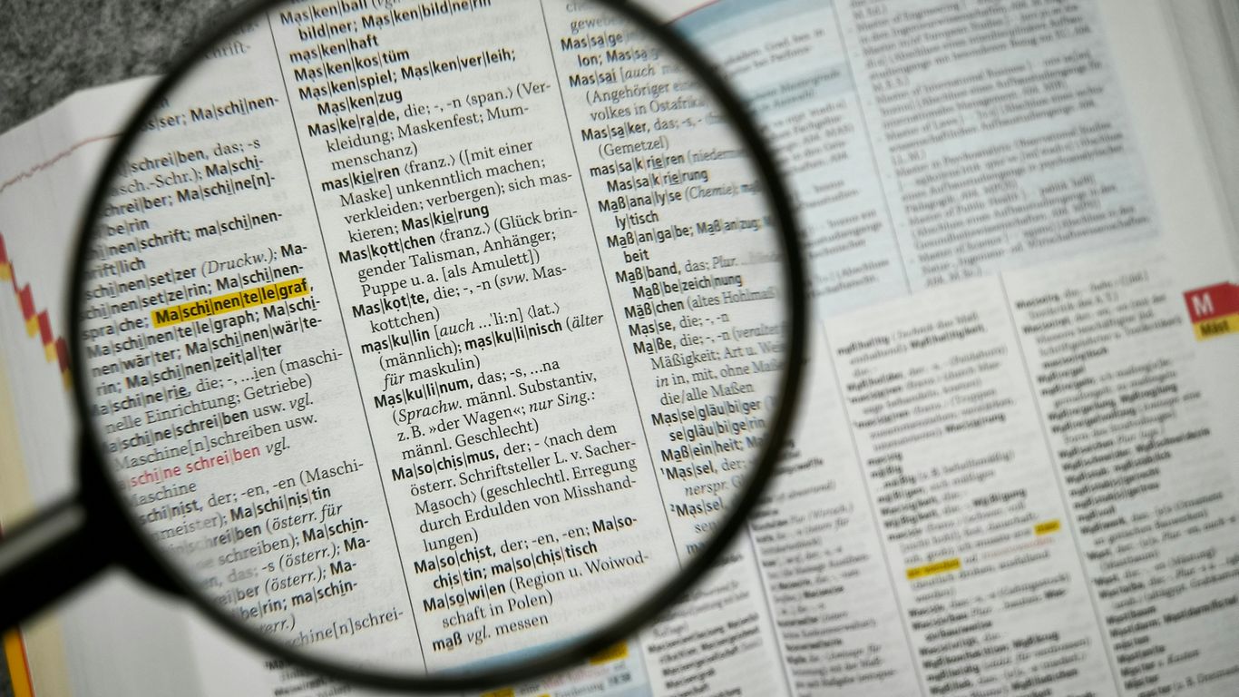 Magnifying glass focuses on a dictionary page.