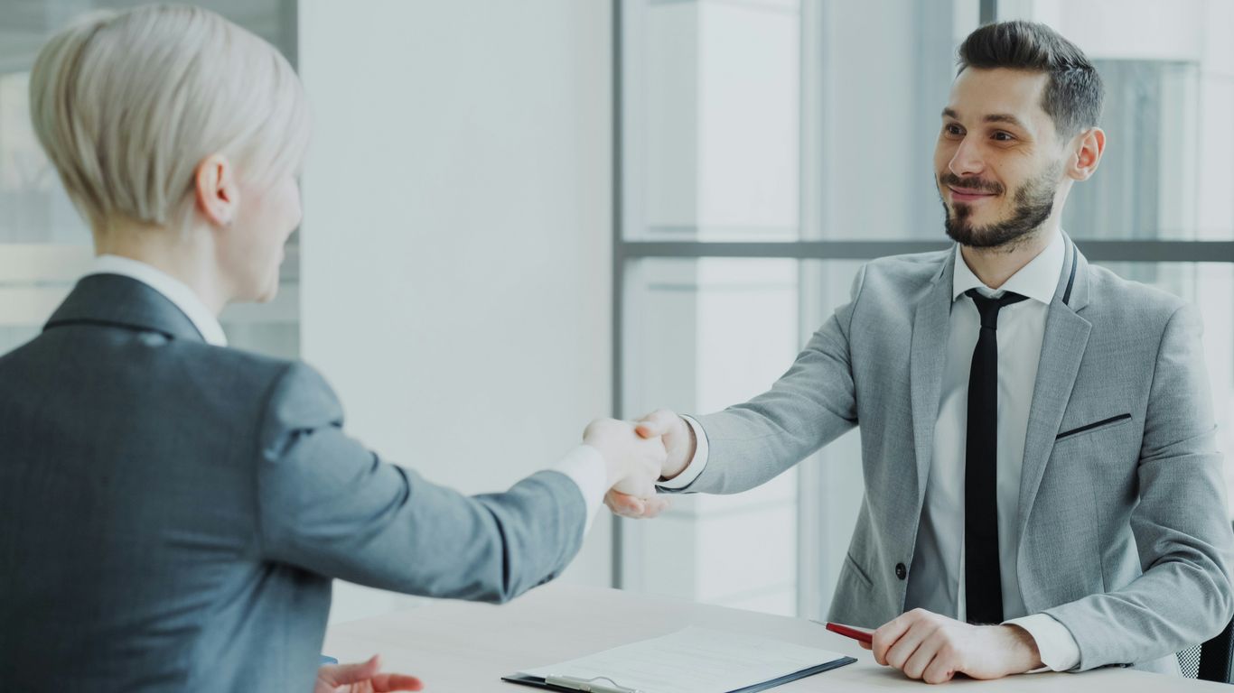 Dos profesionales dándose la mano sobre una mesa.