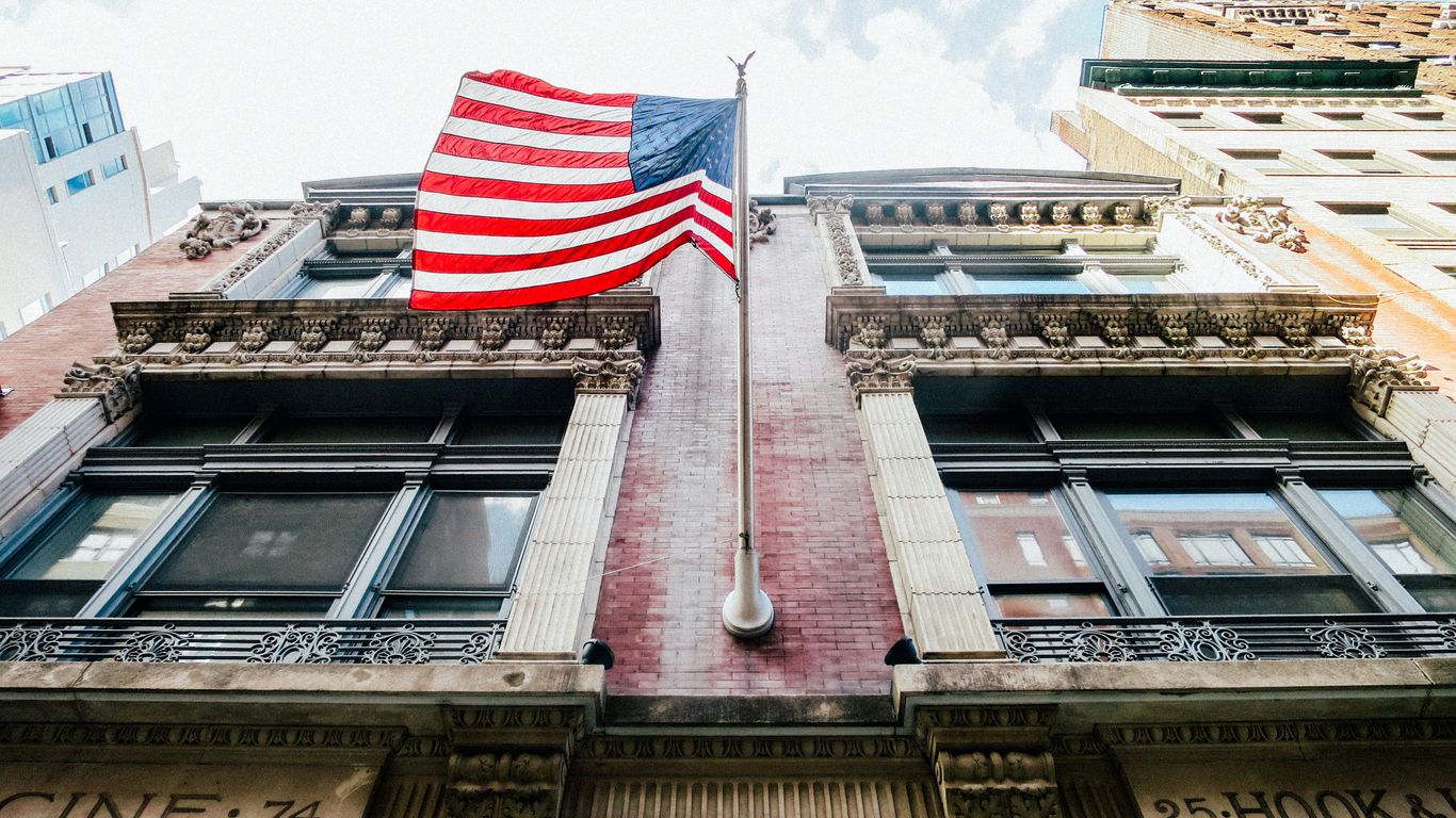 low angle photography of waving U.S.A. flag hang on bricks wall