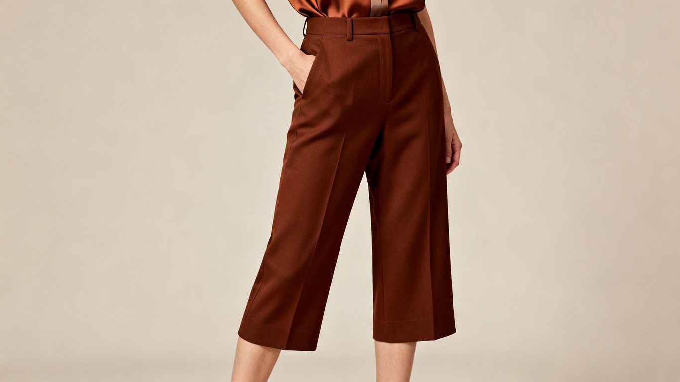 Model wearing brown trousers and a fashionable top.