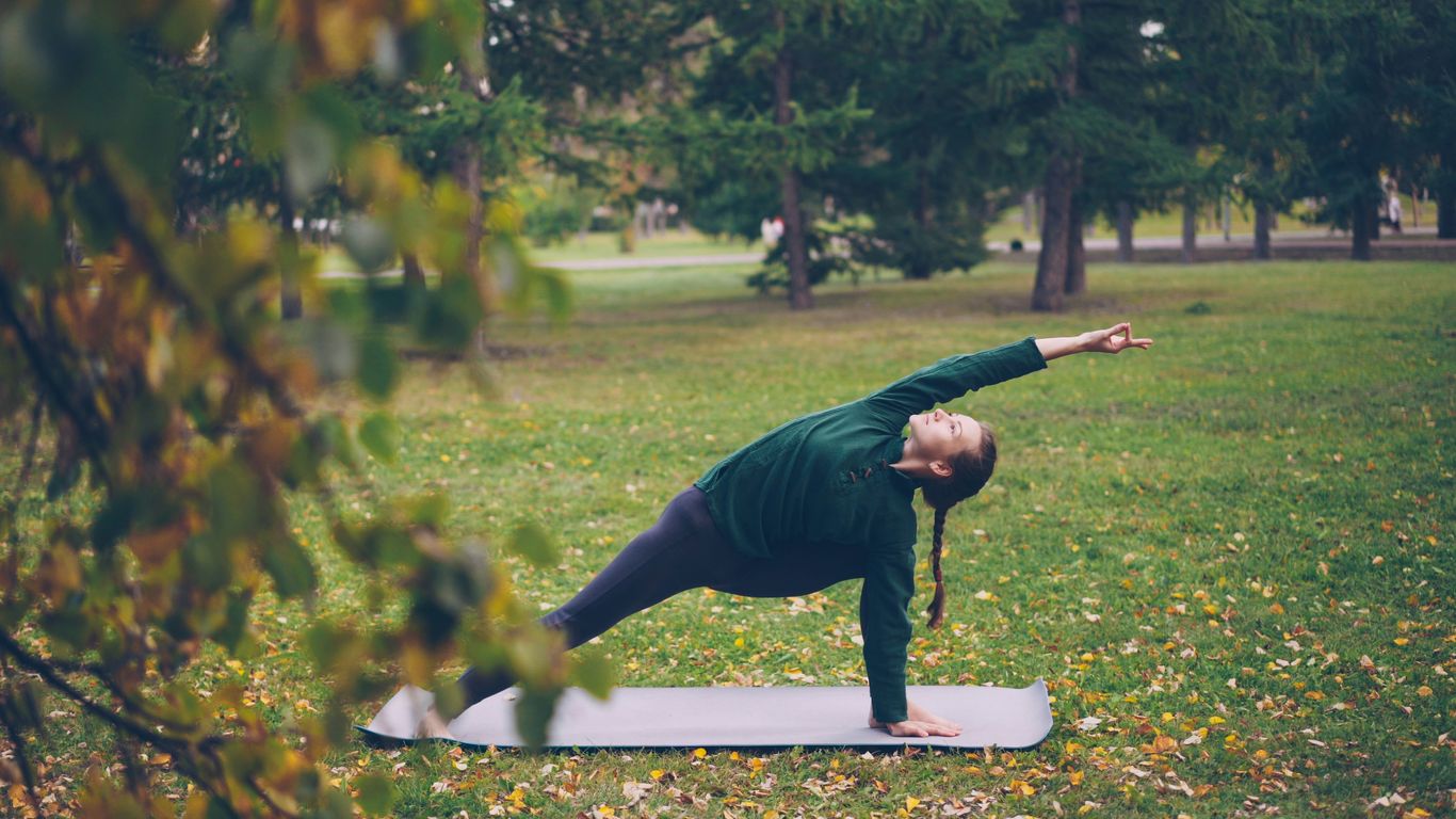 Woman practicing yoga on mat in park