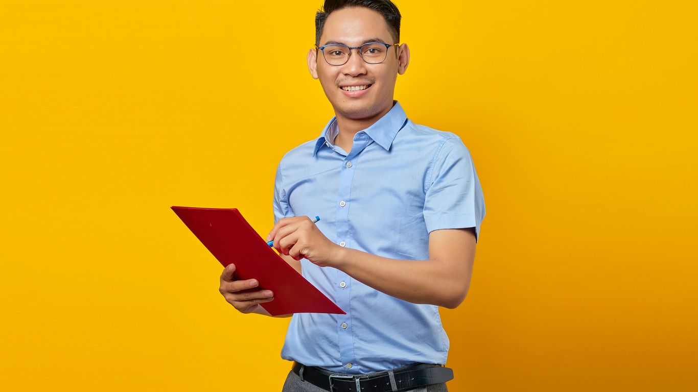 a man in a blue shirt is holding a red folder